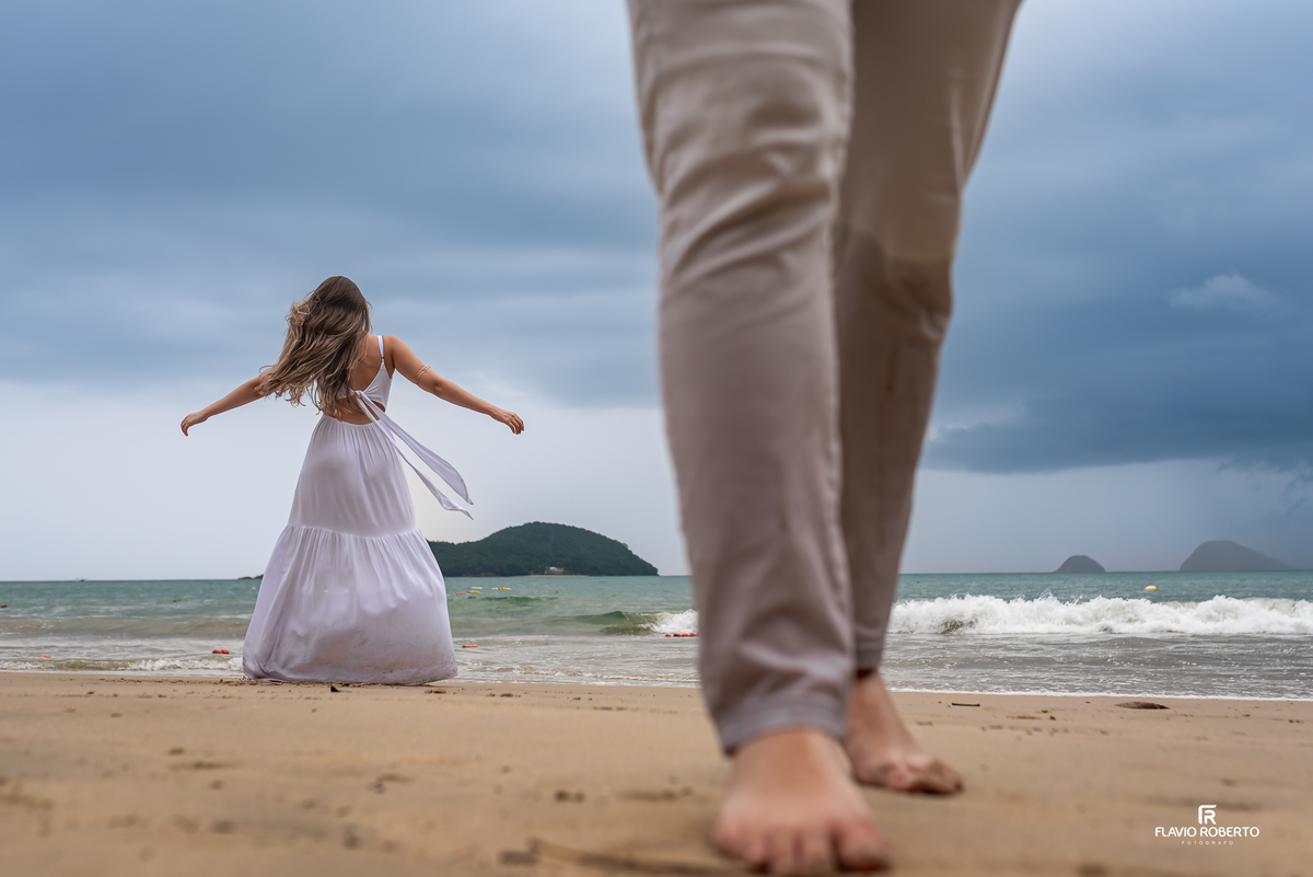 Ensaio pre wedding na praia em Ubatuba com composição criativa e movimento, noiva girando na areia em dia nublado