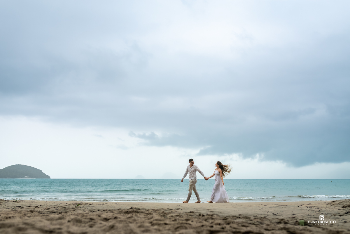 Ensaio pre wedding na Praia da Almada em Ubatuba com casal caminhando de mãos dadas à beira-mar, fotografia natural, leve e cheia de conexão no litoral paulista