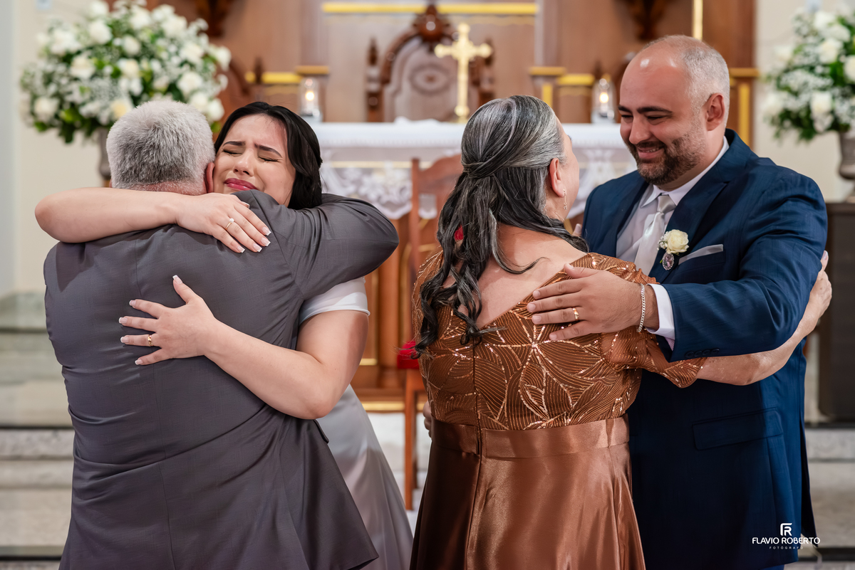 Abraço emocionante dos noivos com os pais após o casamento na igreja em Campos de Cunha