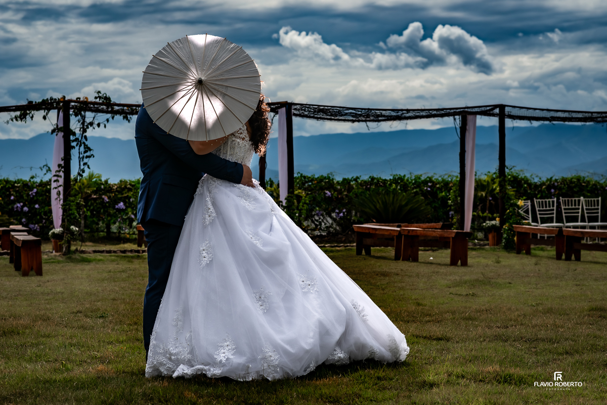 beijo dos noivos com guarda-sol durante ensaio no casamento na Chácara Recanto da Lagoa em Canas
