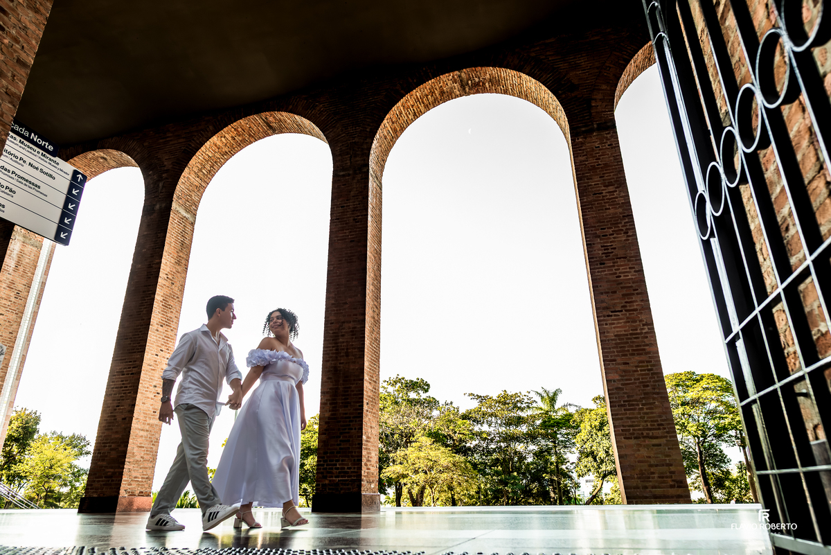 Casal em ensaio pré wedding sob os arcos do Santuário Nacional de Aparecida com luz natural e arquitetura marcante