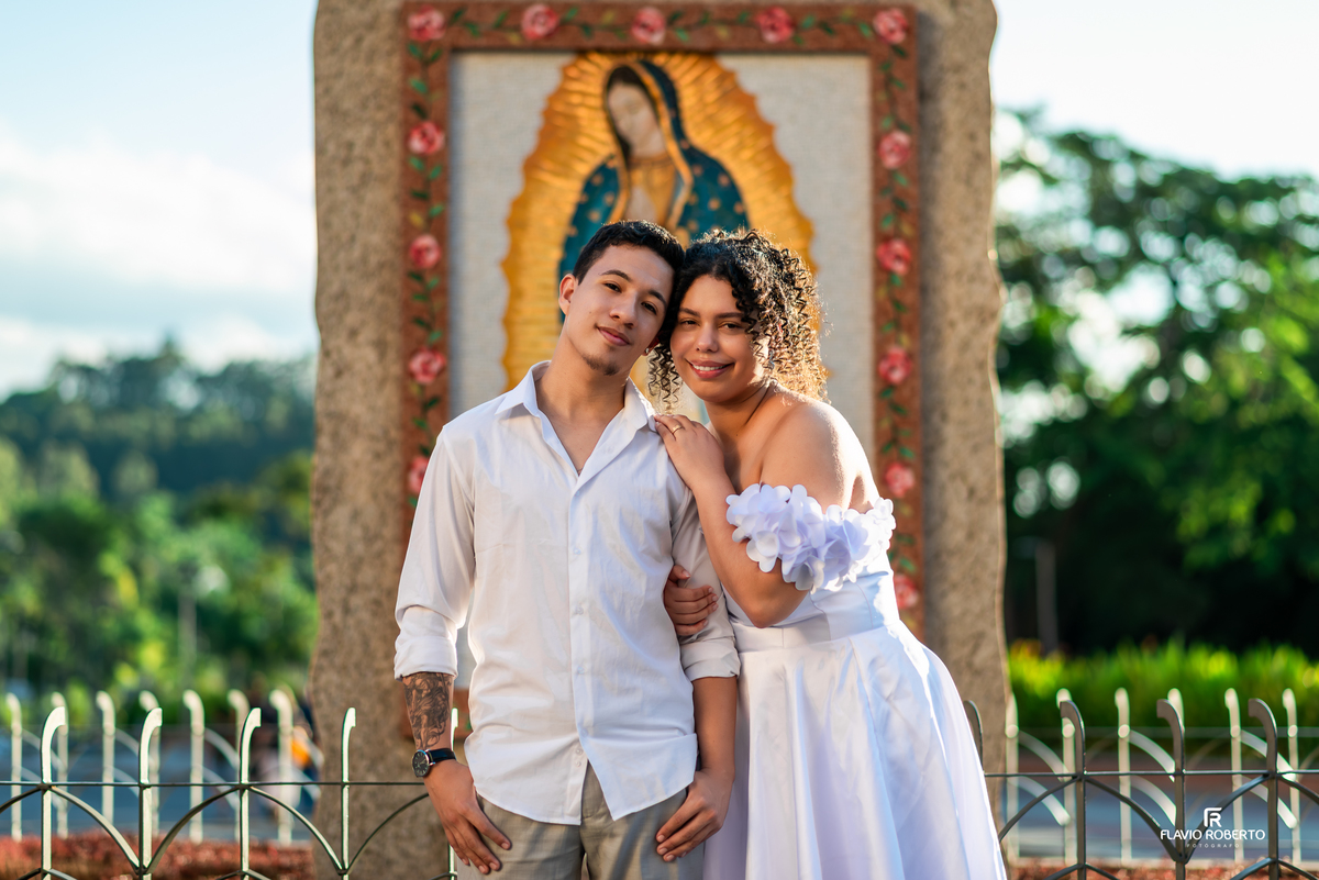 Casal em ensaio pré wedding diante da imagem de Nossa Senhora Aparecida de Guadalupe com iluminação dourada