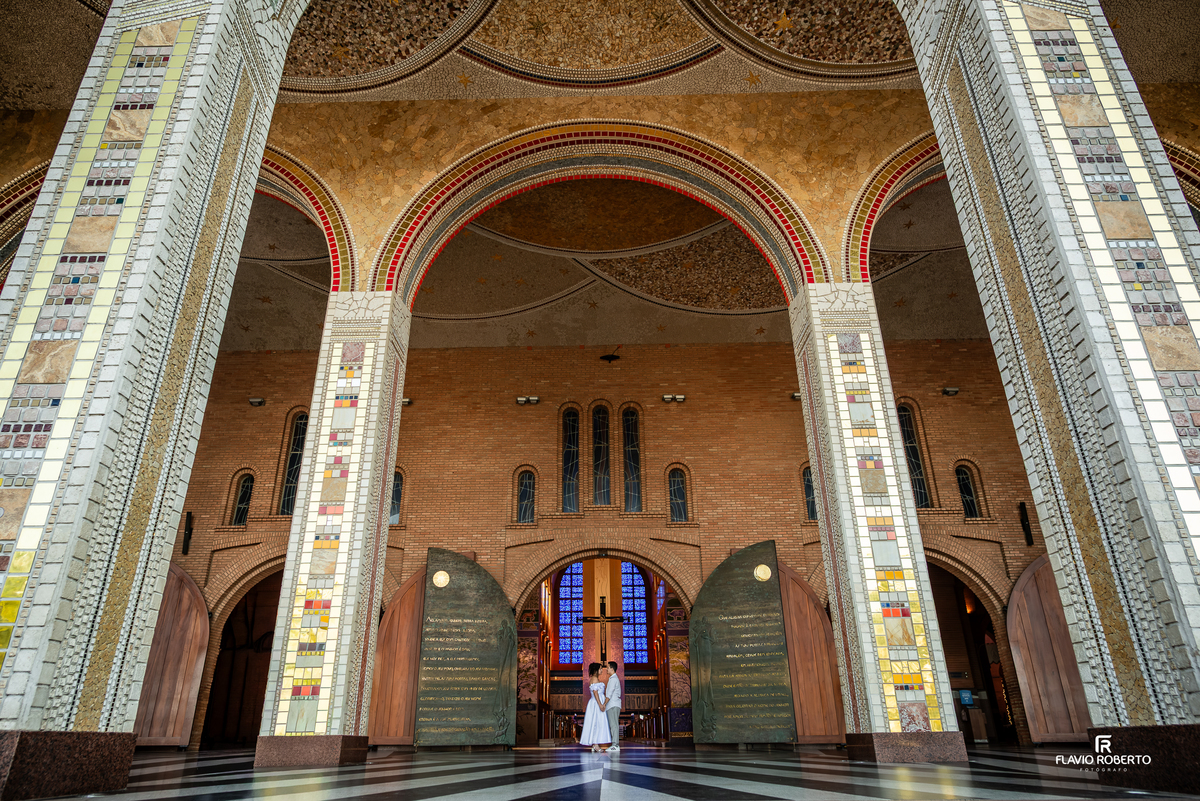 Casal em ensaio pré wedding na entrada do Santuário Nacional de Aparecida destacando a arquitetura imponente