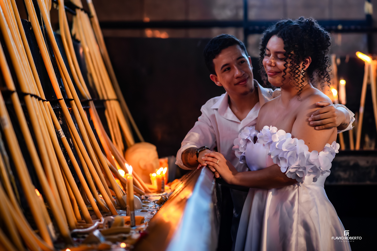 Casal em ensaio pré wedding ao lado das velas no Santuário Nacional de Aparecida com luz quente e ambiente intimista
