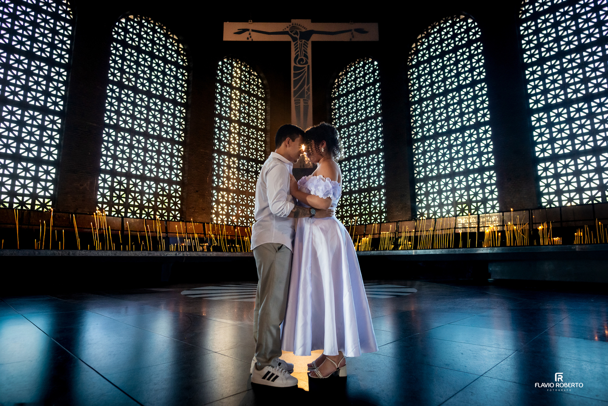 Casal em pre wedding na Capela das Velas do Santuário Nacional de Aparecida com luz suave e clima de fé