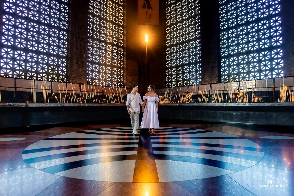 Casal caminhando durante ensaio no Santuário Nacional de Aparecida com composição simétrica e arquitetura marcante