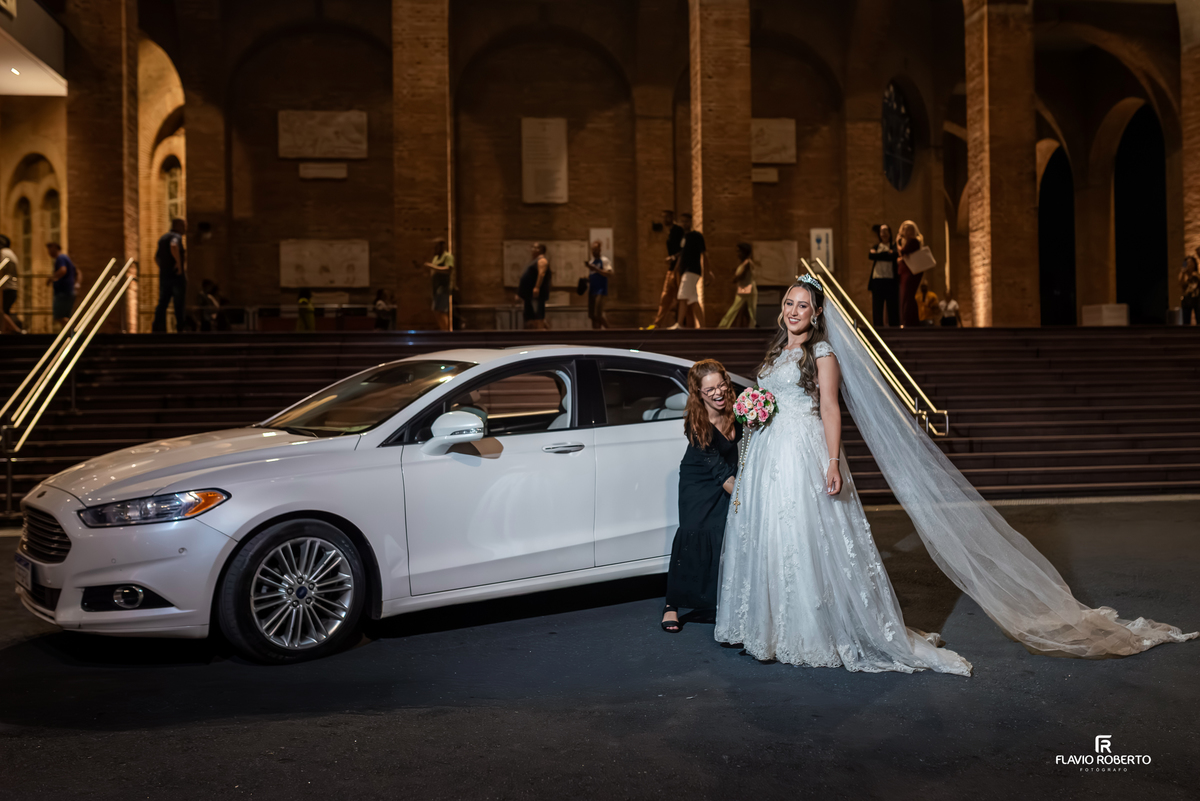 Noiva chegando para casamento no Santuário Nacional de Aparecida à noite com vestido longo e véu