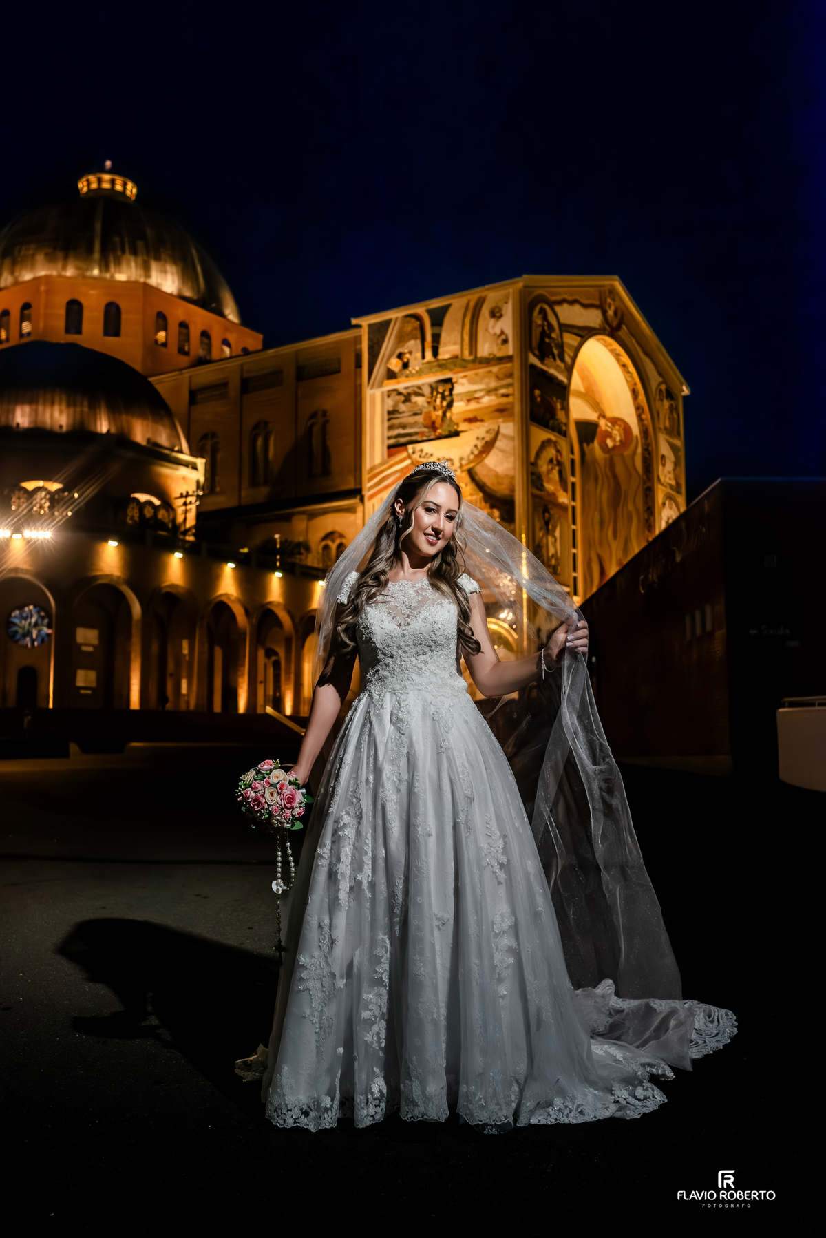 Fotógrafo de casamento no Santuário de Aparecida registra noiva com véu longo em frente à basílica iluminada