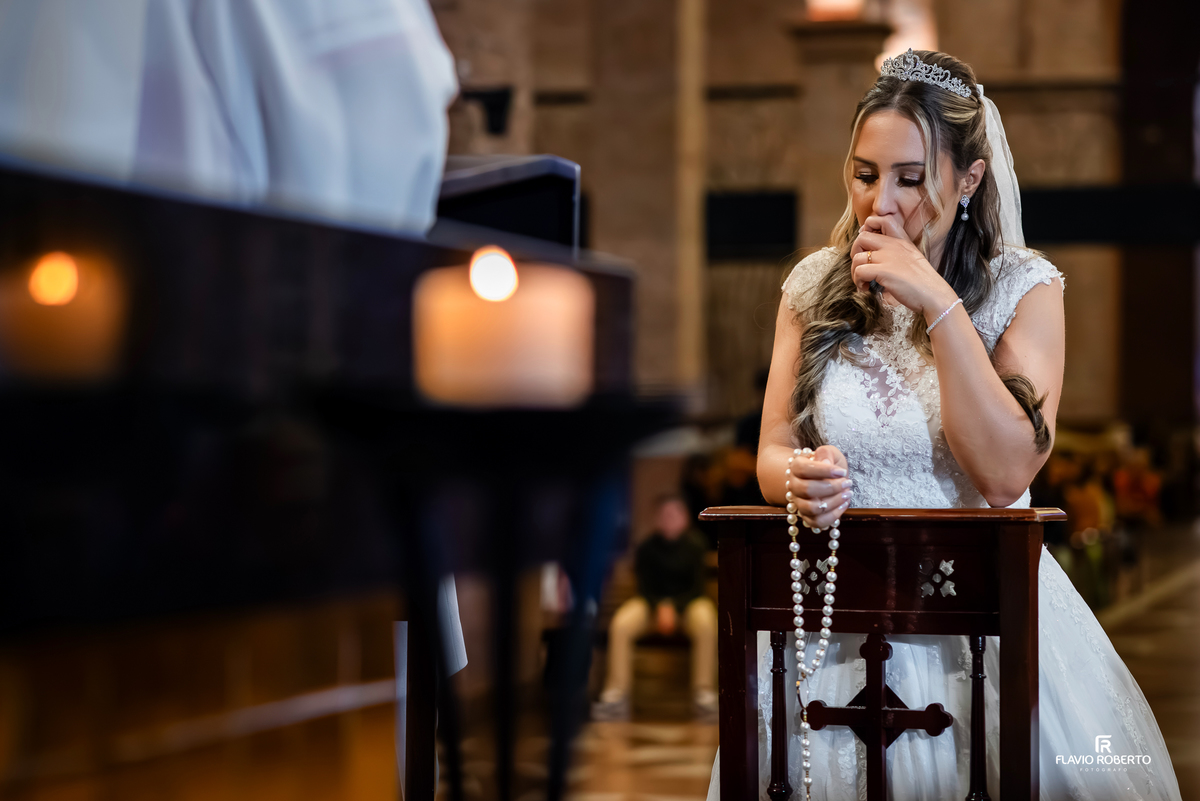 Noiva emocionada segurando terço durante cerimônia de casamento no Santuário de Aparecida