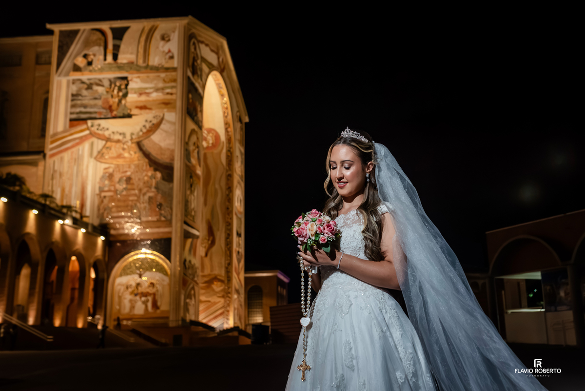 Noiva com terço em mãos em frente ao Santuário Nacional de Aparecida durante ensaio de casamento