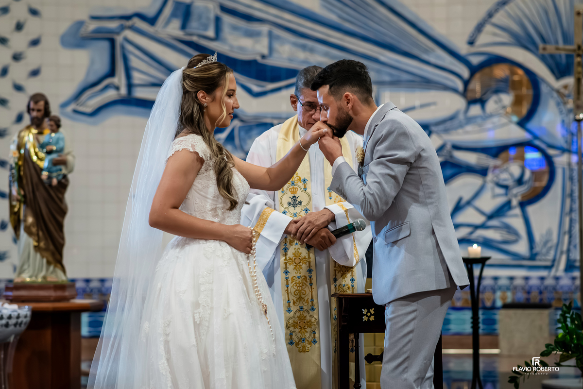 Noivo beijando a mão da noiva durante cerimônia de casamento no Santuário Nacional de Aparecida