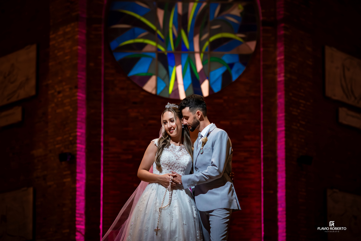 Noivos em frente ao vitral da igreja durante casamento no Santuário Nacional de Aparecida