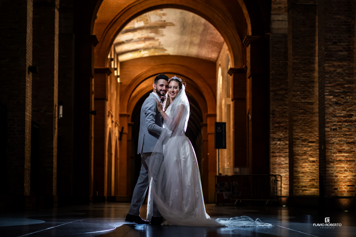 Retrato dos noivos com iluminação dramática no interior do Santuário de Aparecida