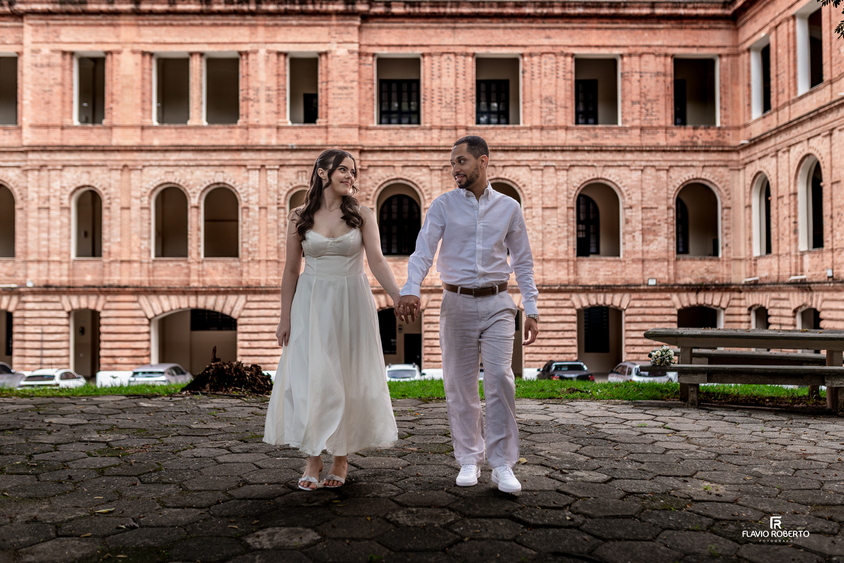 Casal caminhando de mãos dadas na Pousada Bom Jesus em Aparecida com arquitetura clássica ao fundo