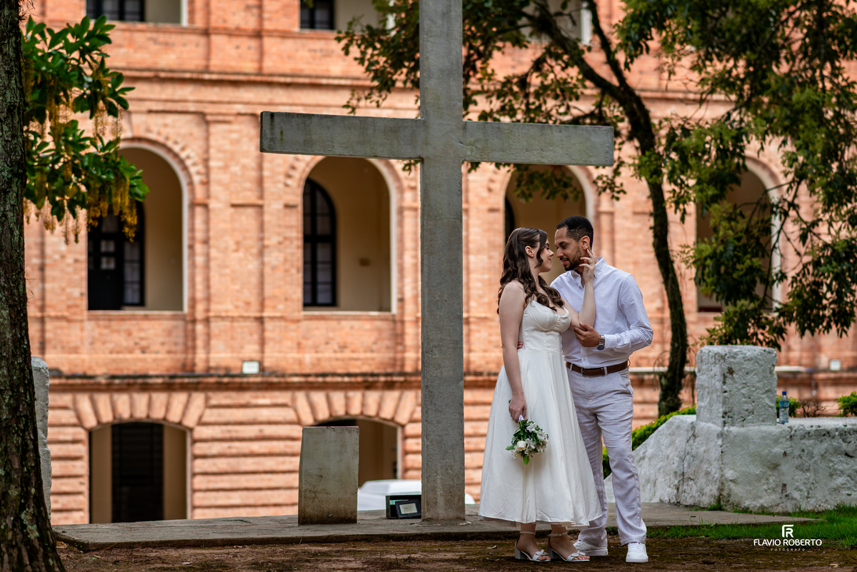 Casal posicionado próximo a cruz em área externa da Pousada Bom Jesus em Aparecida durante pré wedding