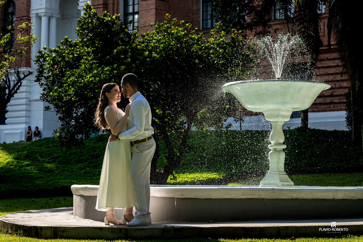 Casal ao lado de fonte iluminada na Pousada Bom Jesus em Aparecida com luz natural valorizando a cena