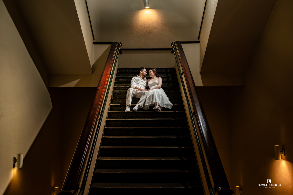 Casal sentado em escadaria interna do Seminário Bom Jesus em Aparecida durante ensaio pré wedding