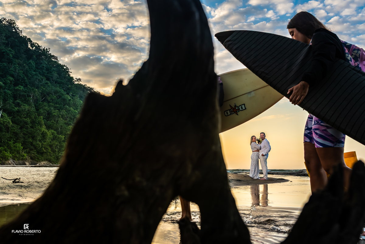 Casal no nascer do sol, entre os surfistas na Praia Itamambuca durante ensaio de casal
