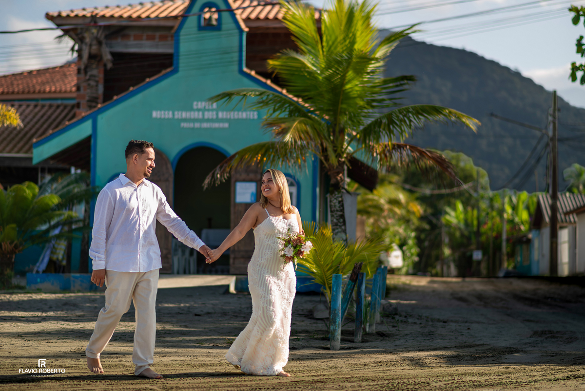 Casal caminhando em frente à Capela Nossa Senhora dos Navegantes