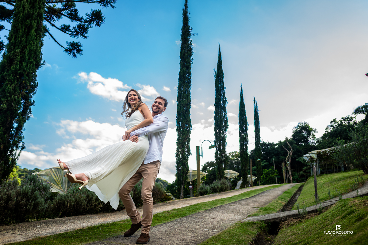 Raissa caminhando entre os vinhedos da Vinícola Essenza enquanto Anderson observa durante ensaio pré wedding em Santo Antônio do Pinhal.