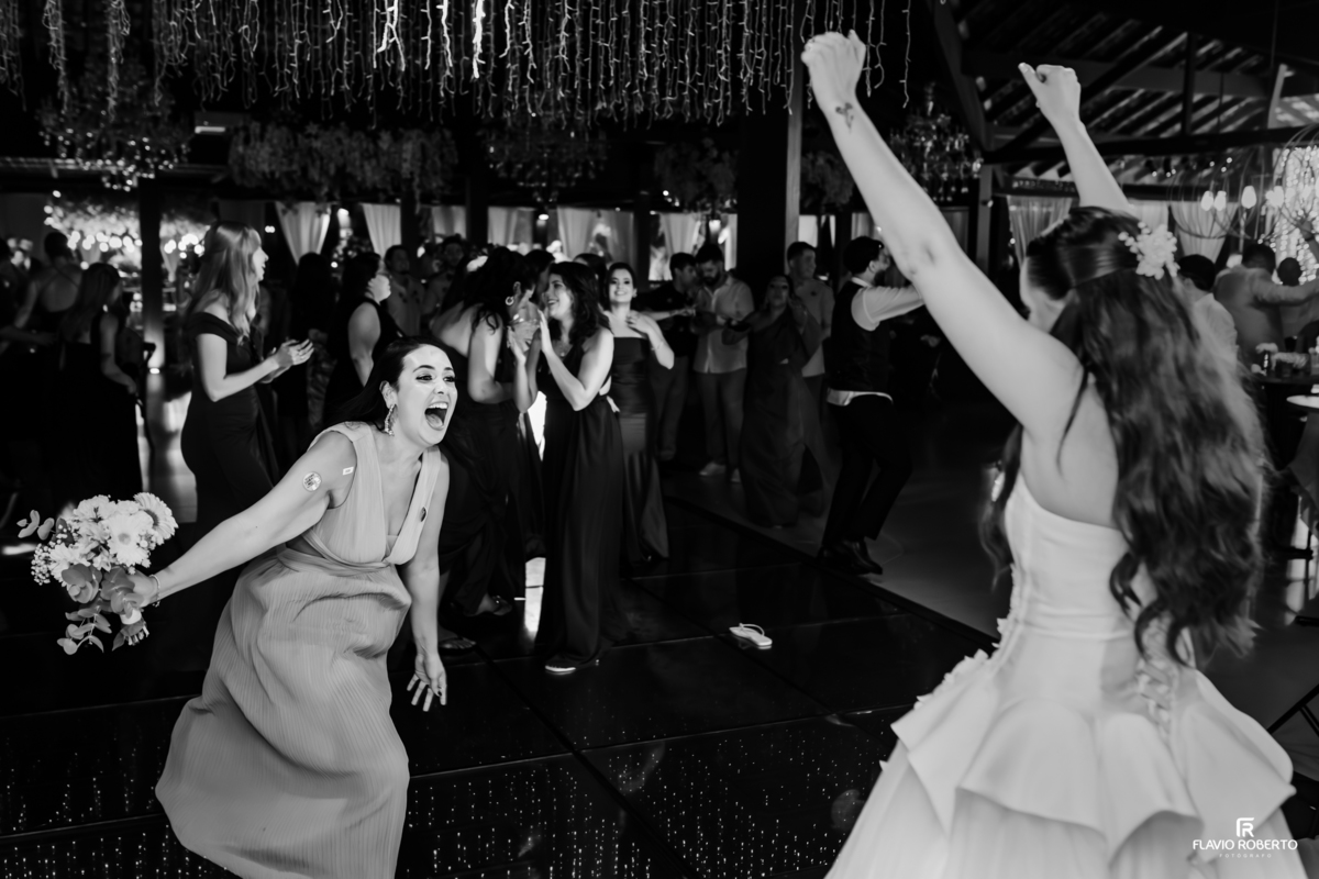 Registro artístico em preto e branco do momento do buquê durante a recepção de casamento no Sítio Tangaroa em Taubaté