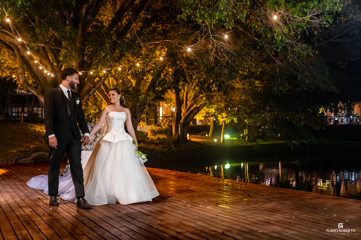 Noivos caminhando pelo deck iluminado do Sítio Tangaroa após a cerimônia de casamento.