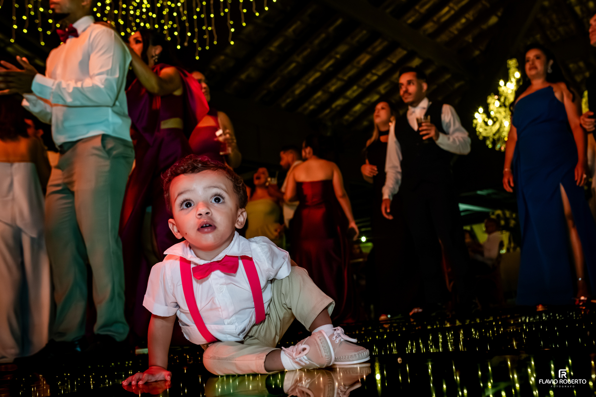 Criança observando encantada a pista de dança iluminada durante a celebração de casamento no Sítio Tangaroa em Taubaté