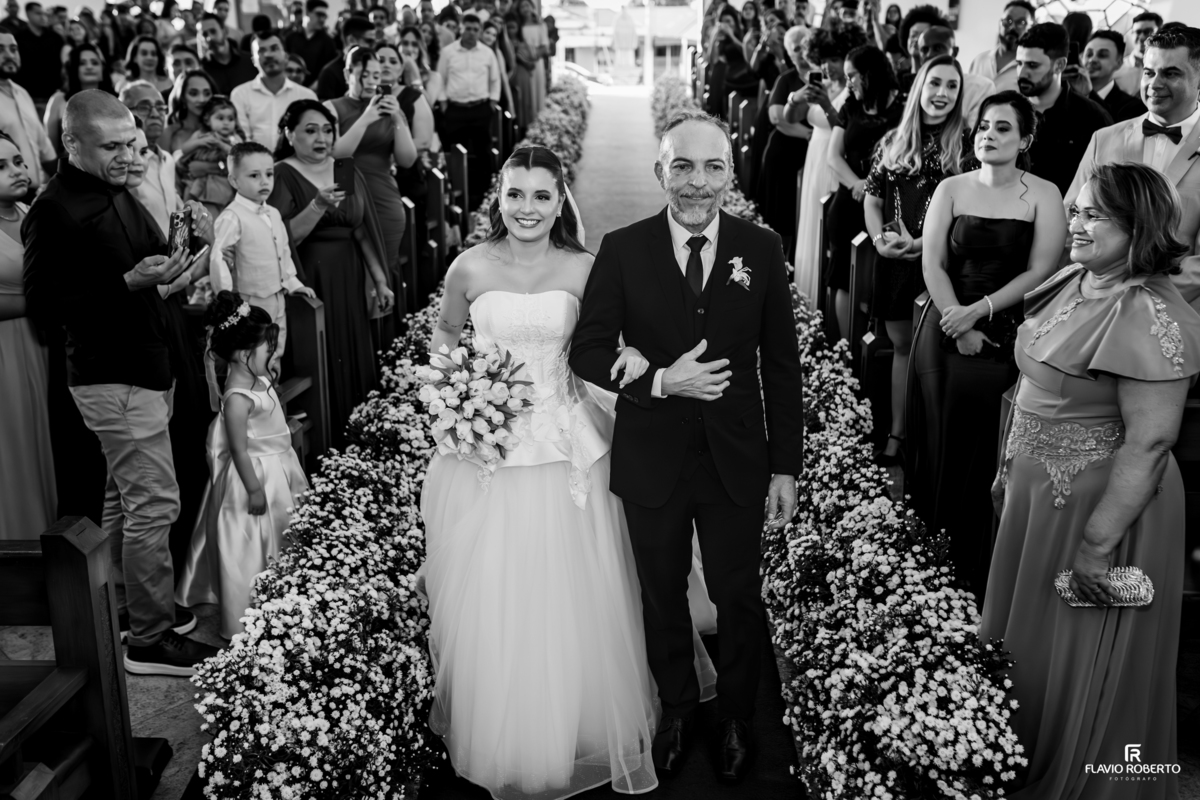 Noiva entrando na igreja acompanhada pelo pai durante casamento em Taubaté.
