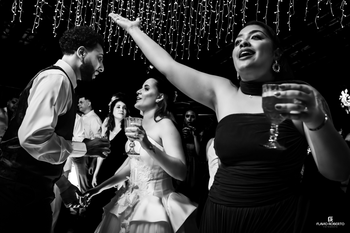 Registro em preto e branco mostrando convidados e noivos aproveitando a pista de dança durante o casamento no Sítio Tangaroa em Taubaté.