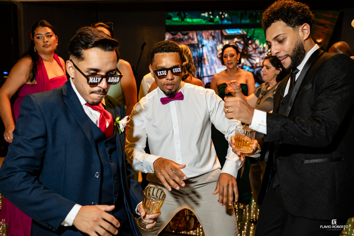 Padrinhos animados dançando e celebrando ao lado do noivo durante a recepção de casamento no Sítio Tangaroa em Taubaté.