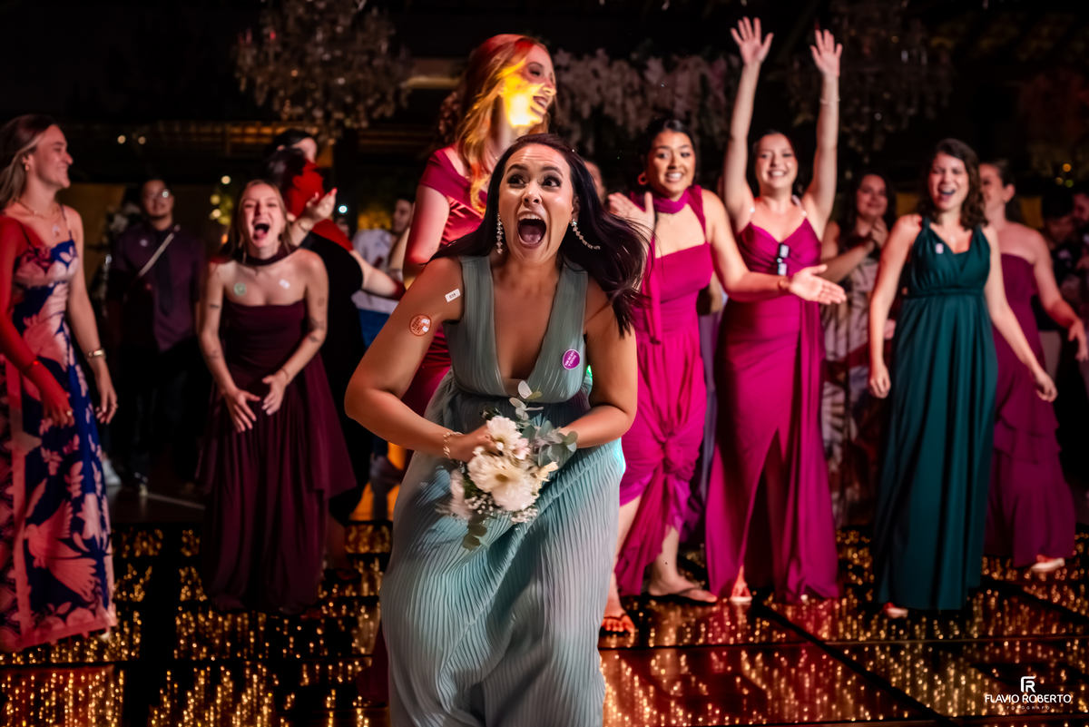 Reação emocionante de convidada ao receber o buquê lançado pela noiva durante a festa de casamento no Sítio Tangaroa em Taubaté.