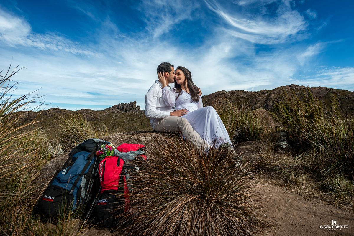 Casal em ensaio de aventura com o Pico das Prateleiras ao fundo.