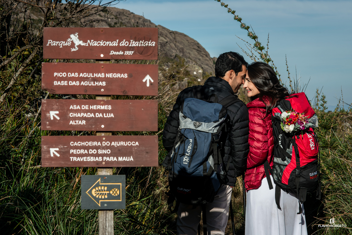 Casal namorando do lado da placa de sinalização dos Picos do Parque Nacional do Itatiaia