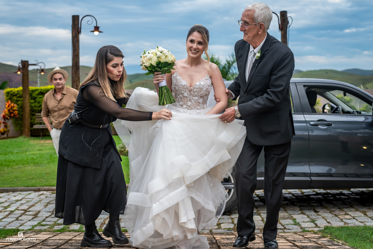 Pai ajudando a noiva Júlia antes da entrada na cerimônia de casamento ao ar livre.