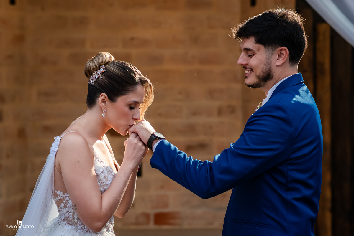 Noiva beija a mão do noivo em momento de carinho durante o casamento no Espaço Aloha em Cruzeiro.