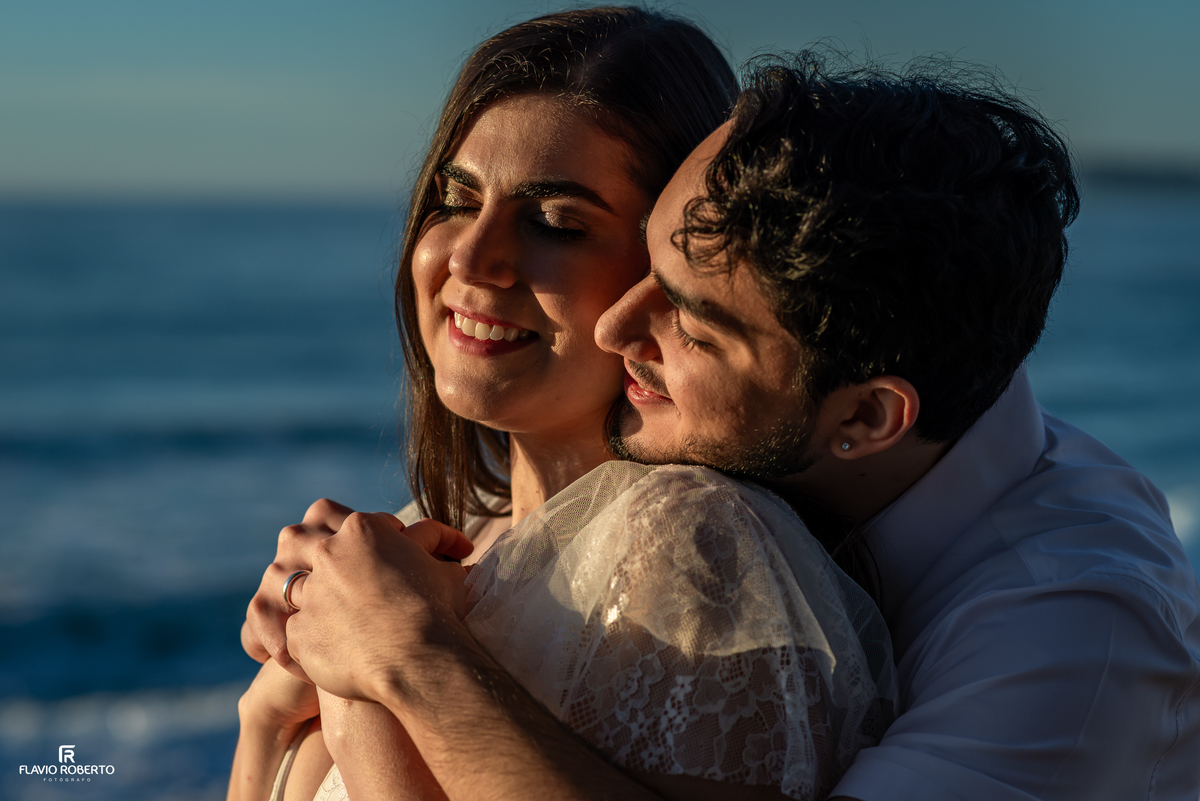 Casal abraçado durante ensaio pré wedding na Praia Vermelha do Norte, em Ubatuba, ao pôr do sol.