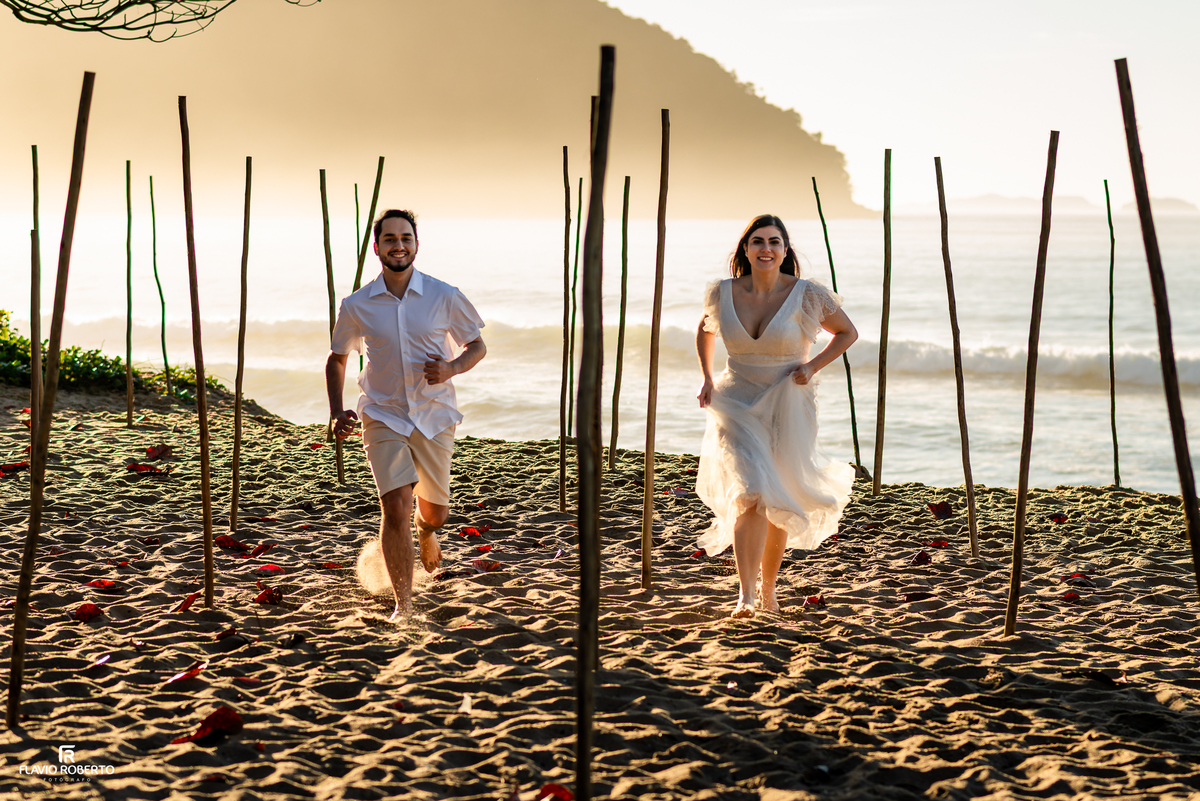 Casal correndo na areia durante ensaio pré wedding na Praia Vermelha do Norte, em Ubatuba.