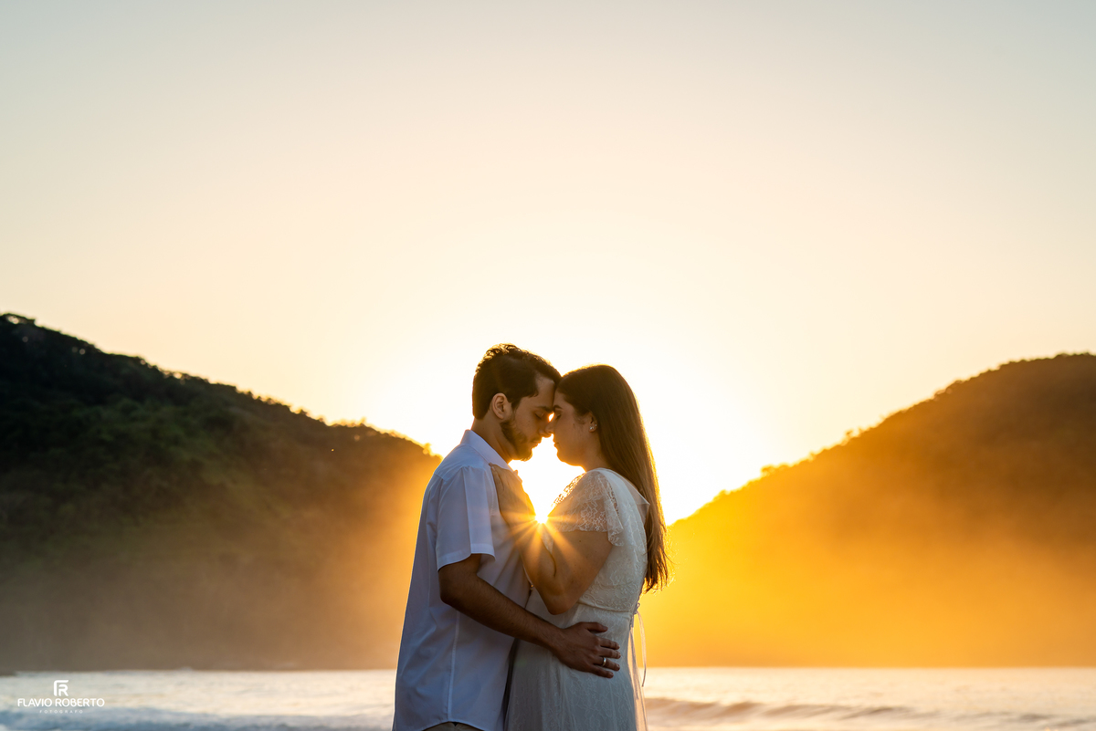 Casal iluminado pela luz dourada do amanhecer na Praia Vermelha do Norte.