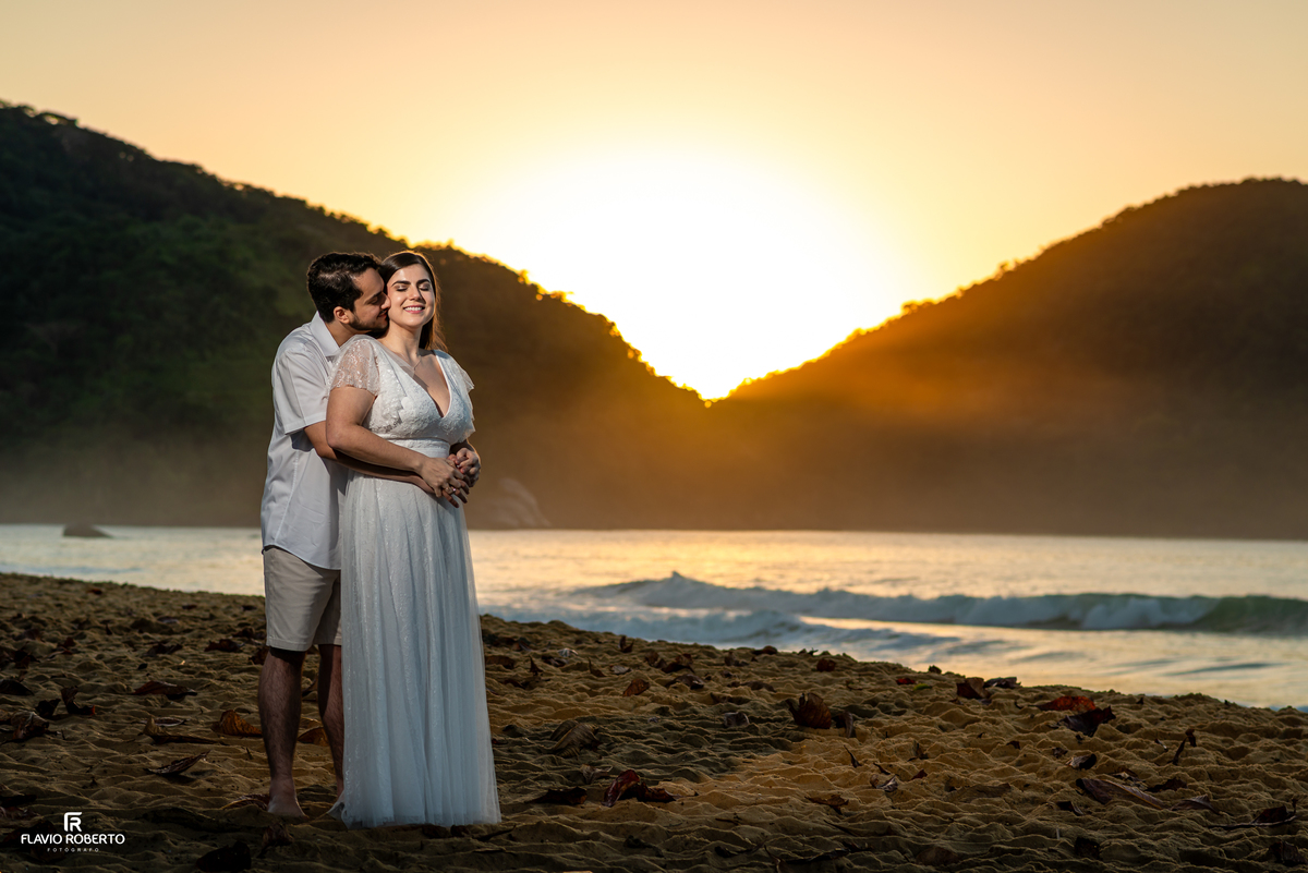Casal abraçado diante do nascer do sol na Praia Vermelha do Norte, em Ubatuba.