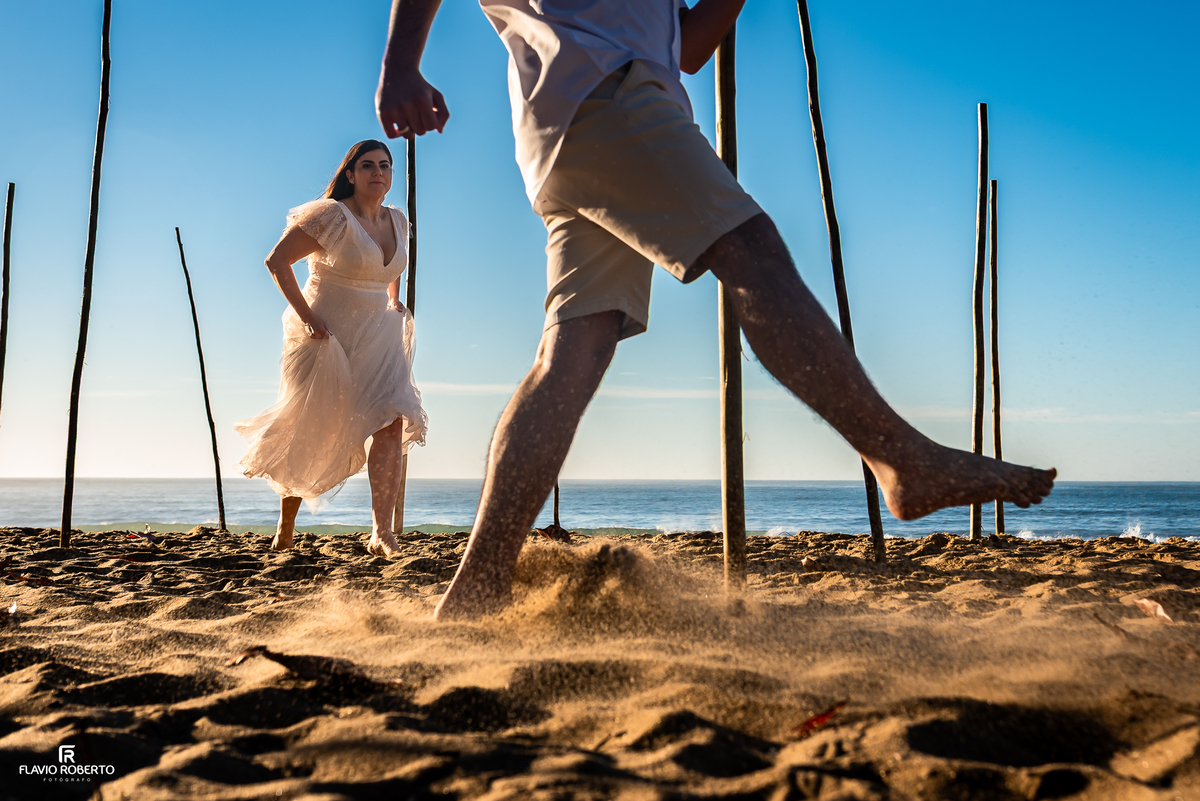 Fotografia criativa de casal correndo na praia durante ensaio pré wedding na Praia Vermelha do Norte, em Ubatuba.