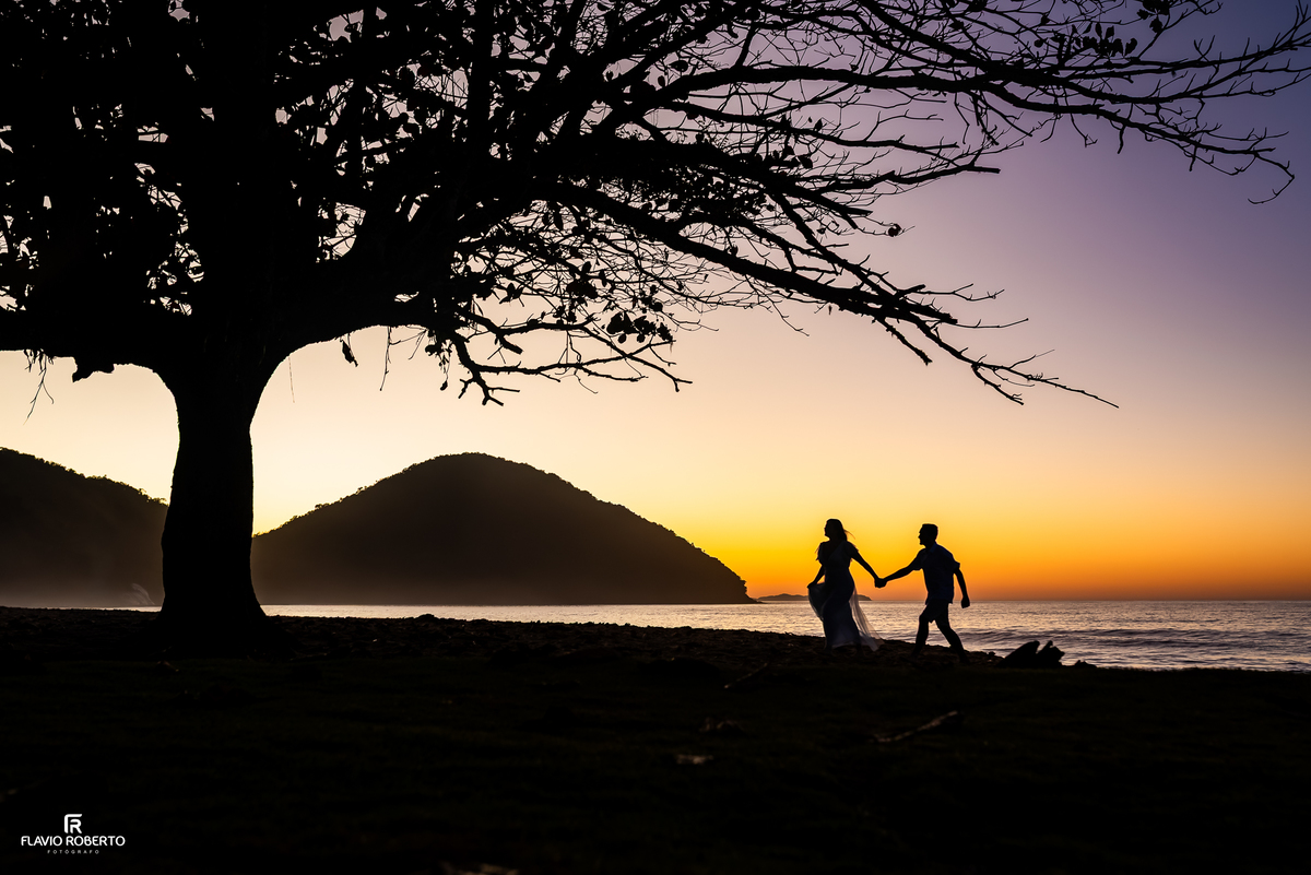 Silhueta do casal caminhando de mãos dadas durante o nascer do sol na Praia Vermelha do Norte.