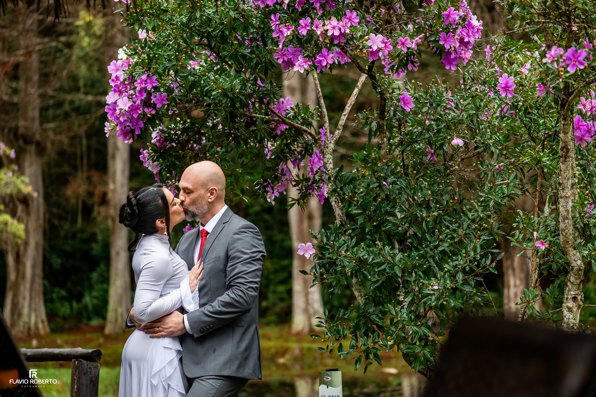 Casal se beijando entre flores durante ensaio pré wedding no Restaurante Arco Íris em Santo Antônio do Pinhal.