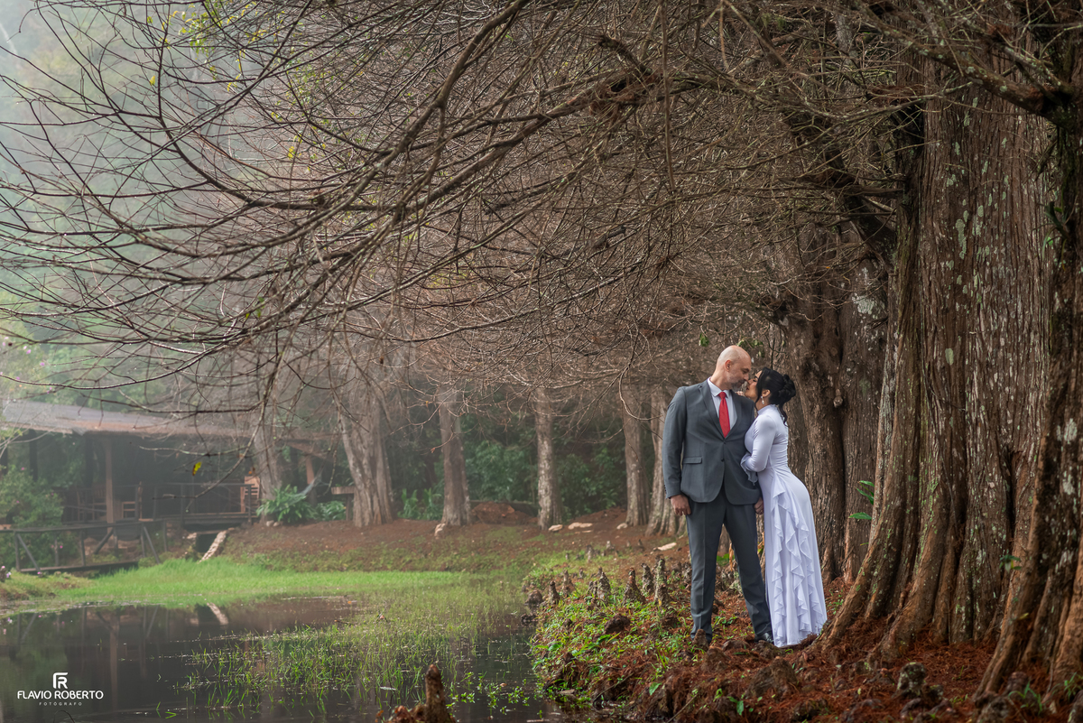 Casal em ensaio pré wedding elegante com lago e árvores no Restaurante Arco Íris em Santo Antônio do Pinhal.