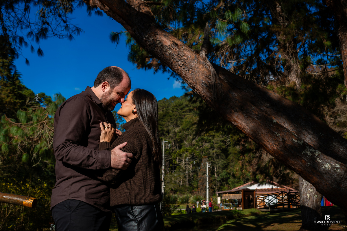 Marcilene e Paulo abraçados sob uma grande árvore durante ensaio em Campos do Jordão.