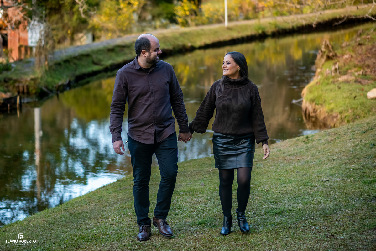 Casal caminhando de mãos dadas às margens do lago no Horto Florestal de Campos do Jordão.