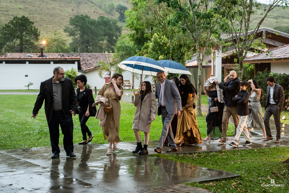 Convidados chegando sob a chuva para o casamento no Recanto do Bosque em Guaratinguetá