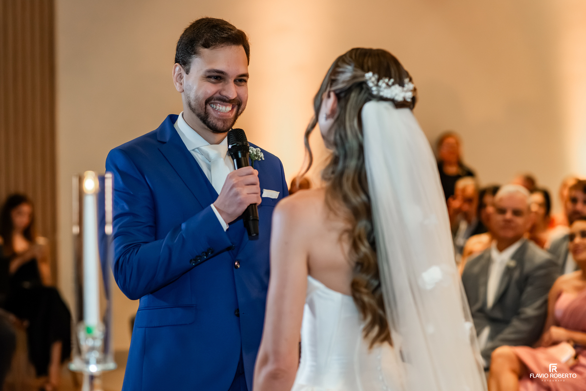 Noivo sorrindo durante os votos de casamento diante da noiva no Recanto do Bosque, em Guaratinguetá.