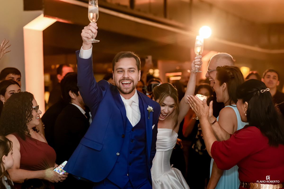 Noivos brindam com taças durante entrada animada na festa de casamento no Recanto do Bosque.