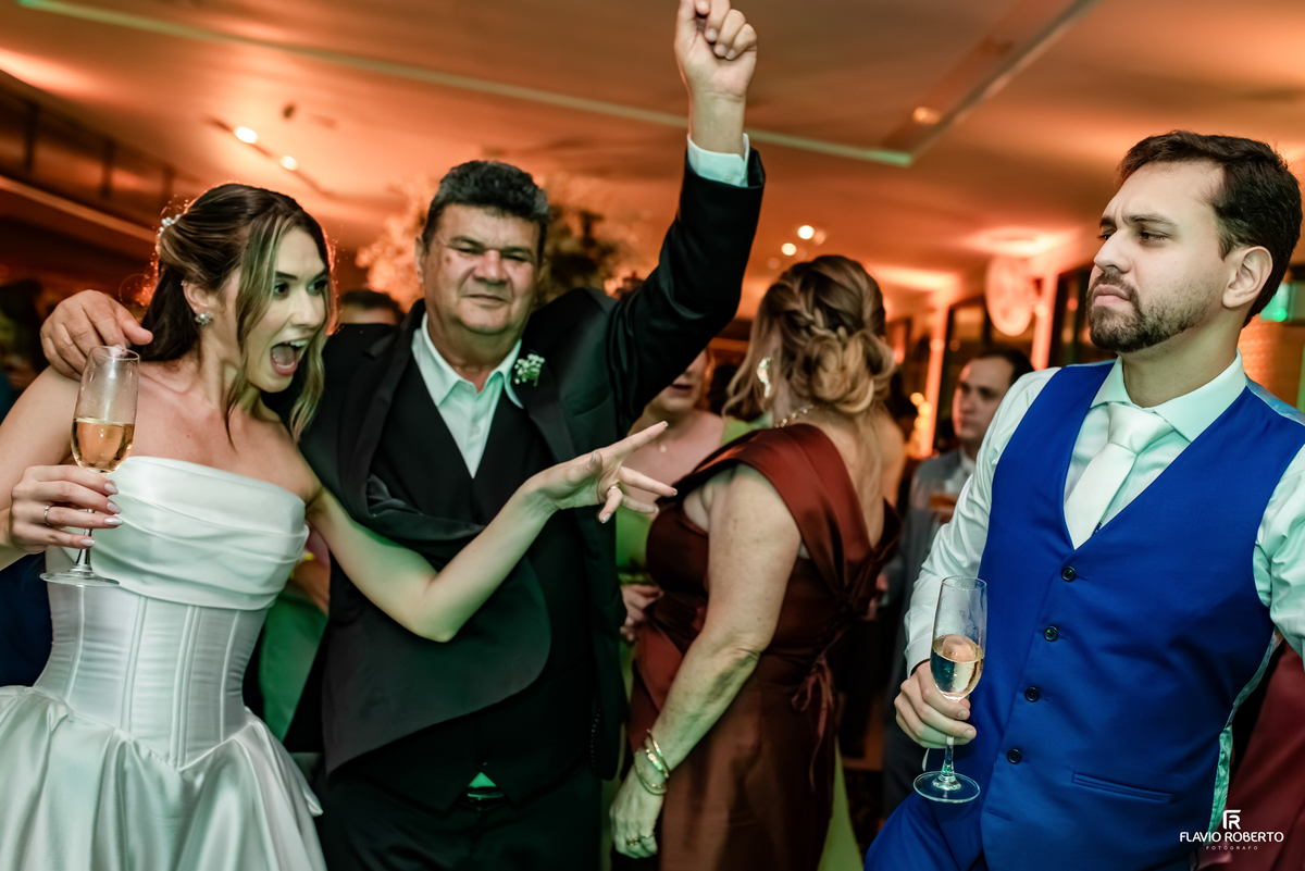 Noiva e convidadas se divertem fazendo selfie enquanto o noivo dança durante festa de casamento no Recanto do Bosque.