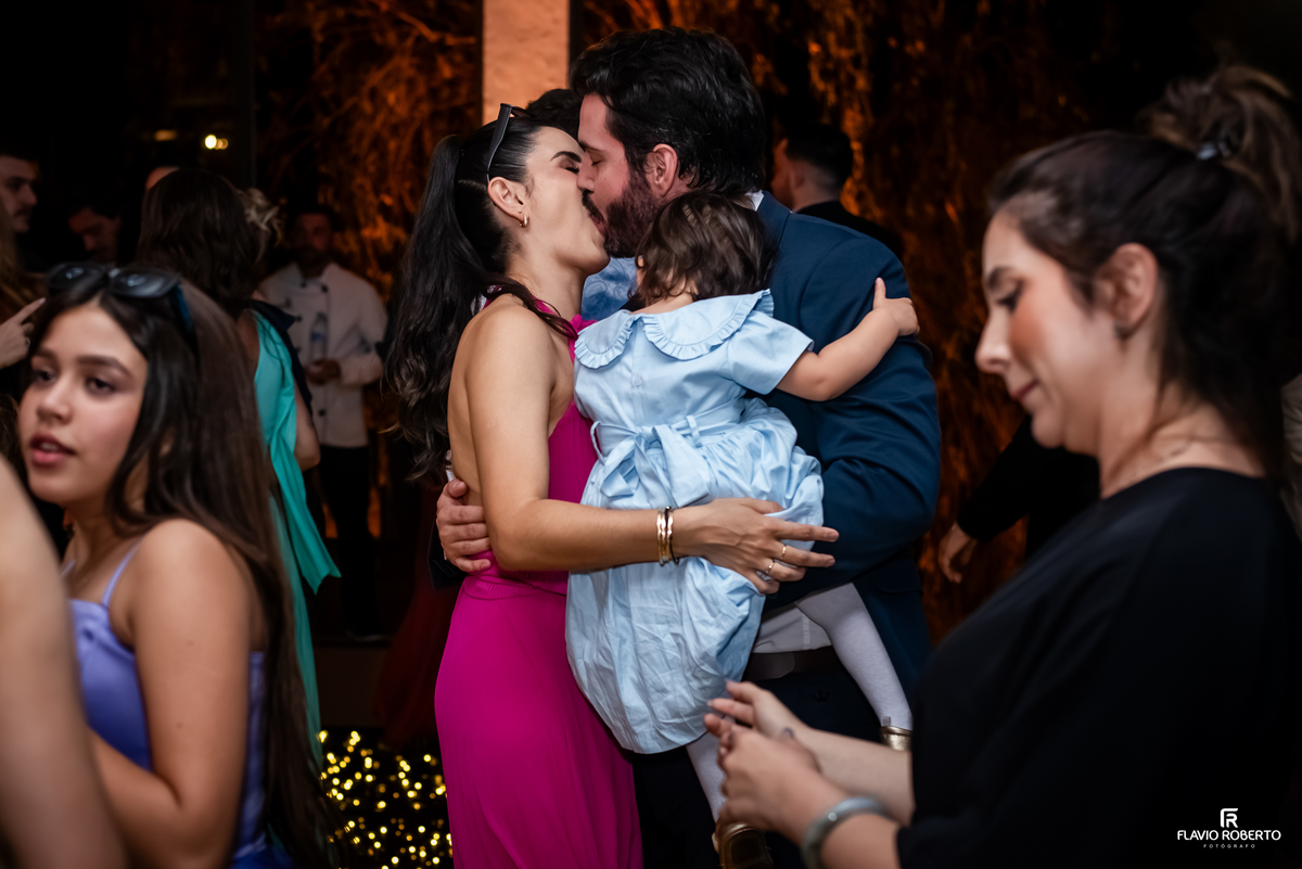 Convidados se beijando com criança no colo durante festa de casamento em Guaratinguetá